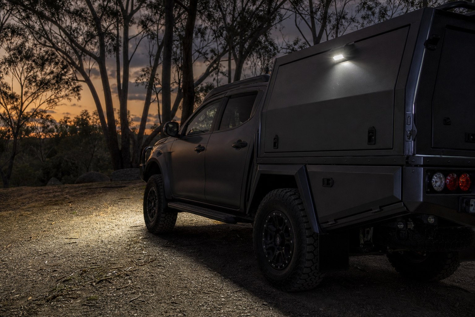 Exterior canopy light illuminating the ground beside a parked 4x4