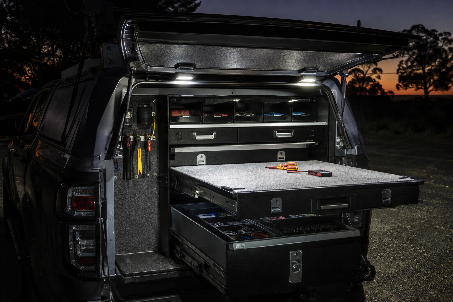 Work lights illuminating an organised vehicle tool drawer and bench