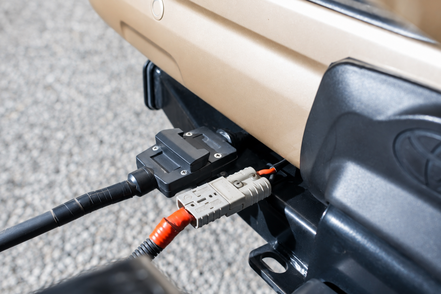 Clean grey Anderson connection beside a flat trailer plug beneath a vehicle bumper
